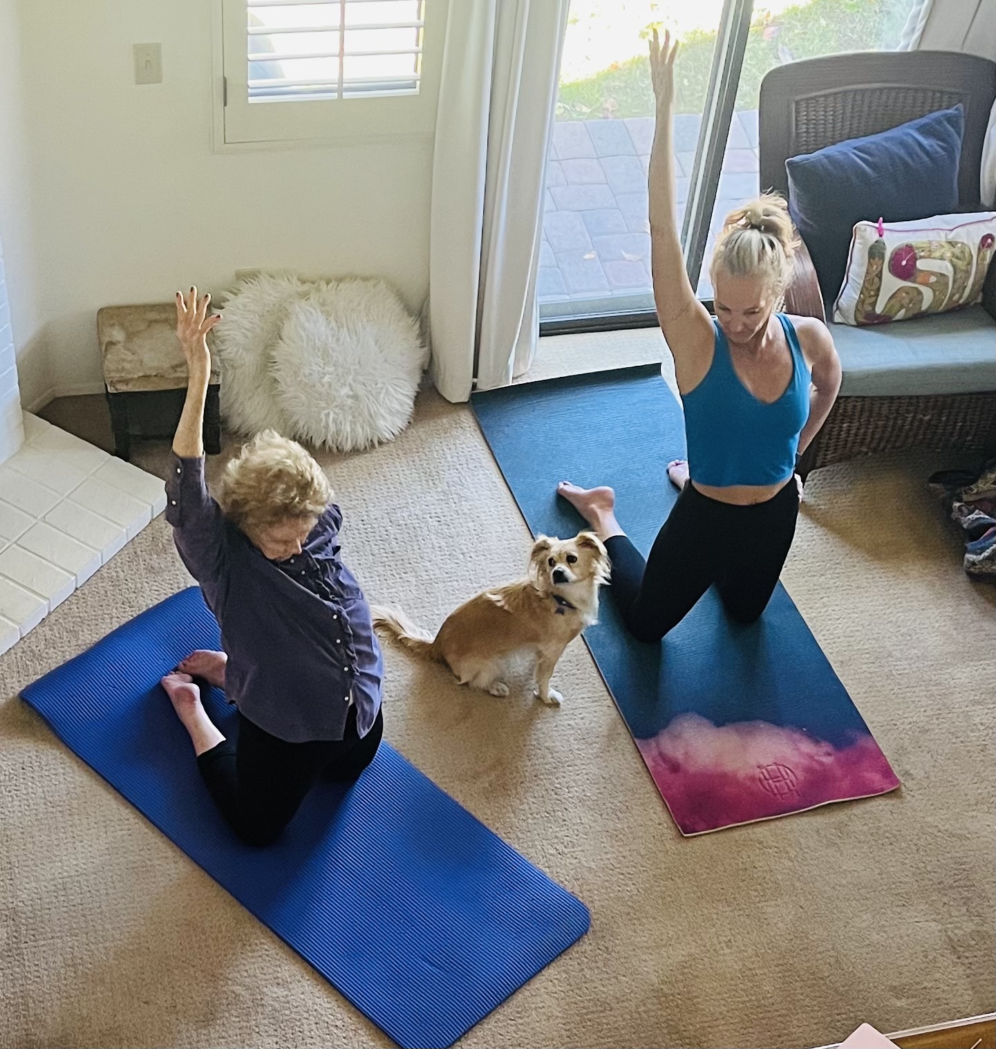 Two people practicing gentle somatic movement indoors with a dog nearby