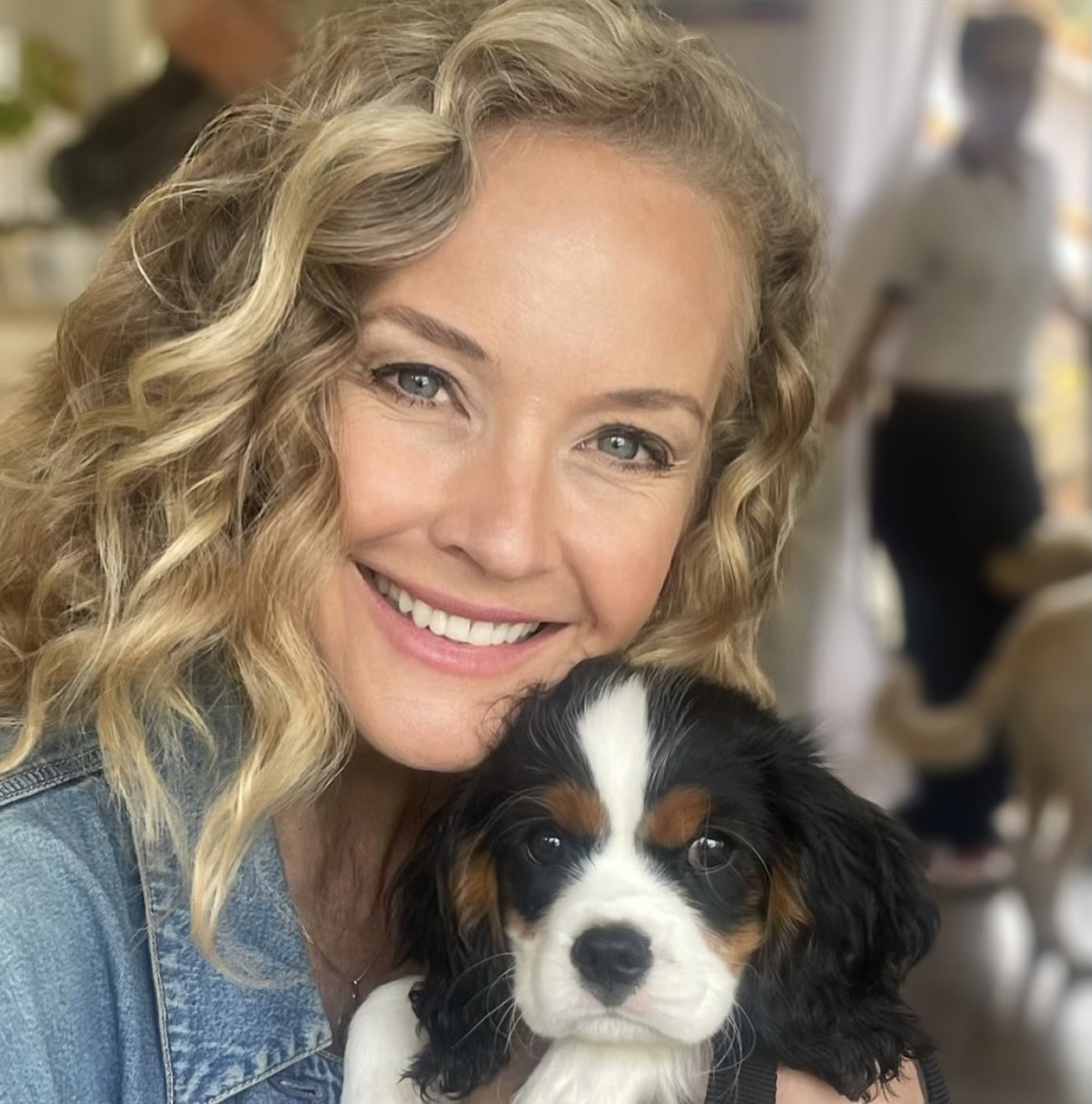 Savannah Miller smiling while holding a Cavalier King Charles spaniel puppy